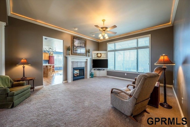 carpeted living room featuring ceiling fan, ornamental molding, and a tiled fireplace