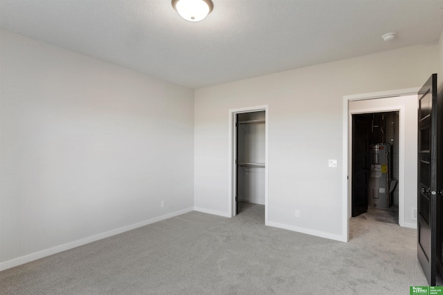 unfurnished bedroom with electric water heater, light colored carpet, and a closet