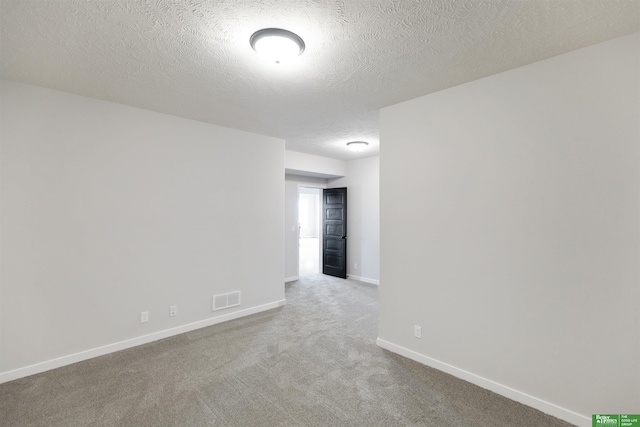 carpeted empty room featuring a textured ceiling