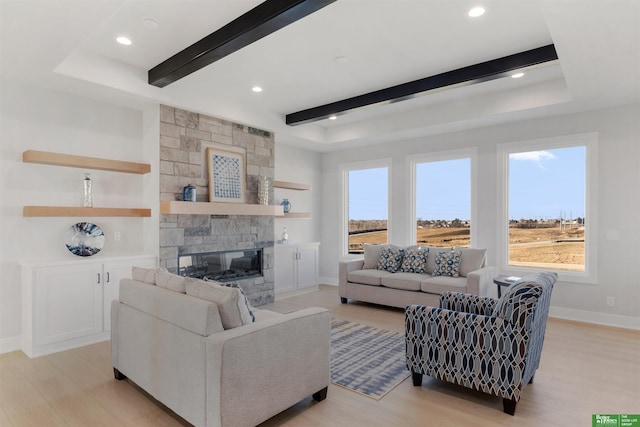 living room with beamed ceiling, a stone fireplace, light hardwood / wood-style floors, and a wealth of natural light