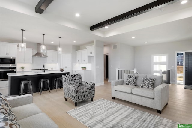 living room with sink, beam ceiling, and light hardwood / wood-style floors