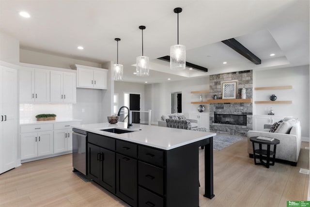 kitchen featuring white cabinetry, dishwasher, sink, a center island with sink, and light wood-type flooring