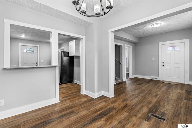 interior space featuring dark hardwood / wood-style flooring, a textured ceiling, and an inviting chandelier