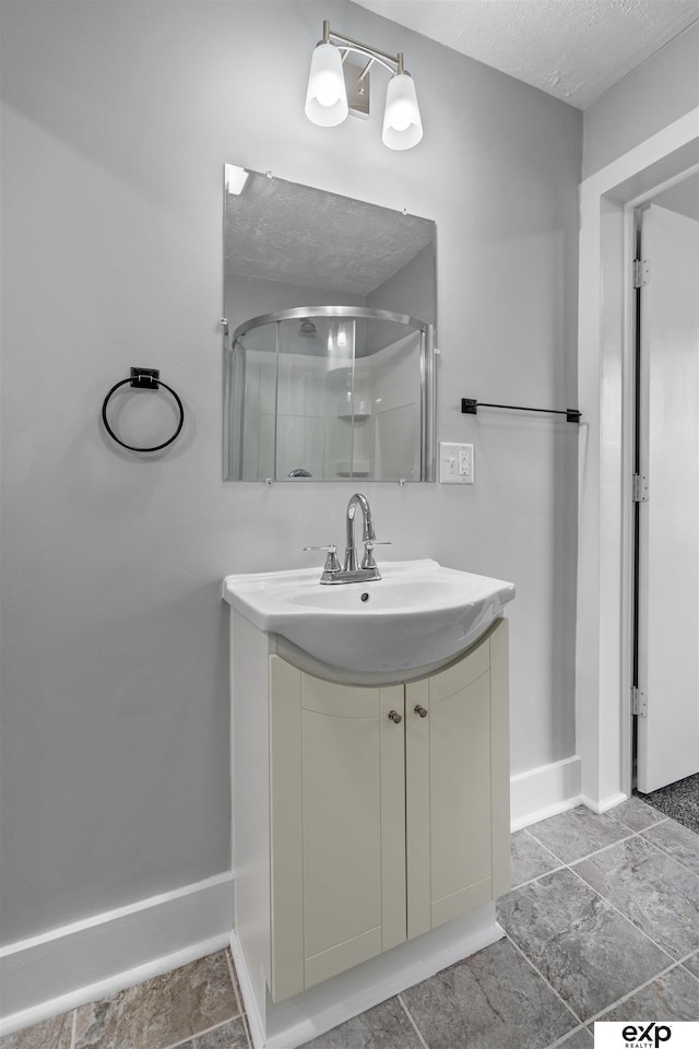 bathroom featuring vanity, a textured ceiling, and a shower with shower door