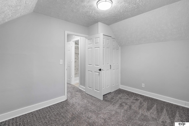 bonus room featuring vaulted ceiling, a textured ceiling, and dark colored carpet