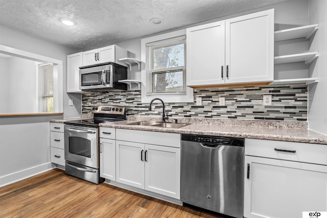 kitchen featuring stainless steel appliances, white cabinetry, sink, and light wood-type flooring