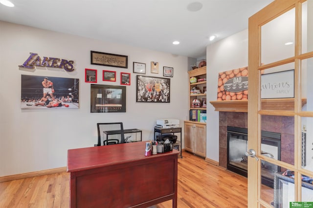 office space featuring a tiled fireplace and light hardwood / wood-style flooring