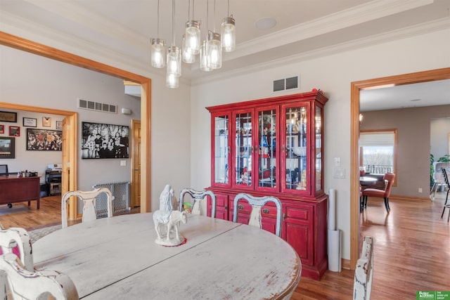 dining space featuring radiator heating unit, crown molding, and wood-type flooring