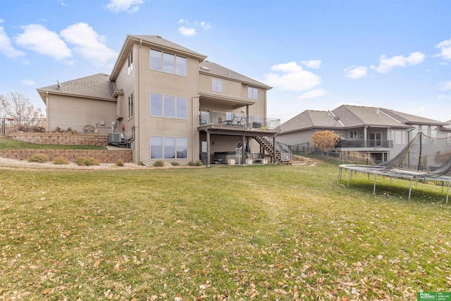 rear view of property with a yard, a deck, a trampoline, and central air condition unit