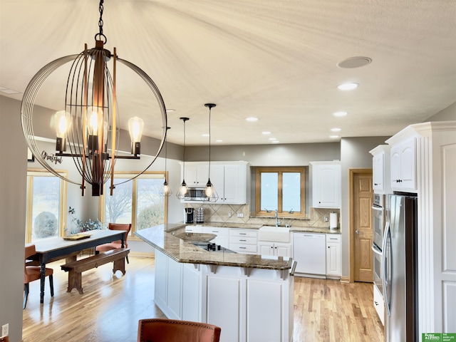 kitchen with kitchen peninsula, dark stone counters, white cabinets, and appliances with stainless steel finishes