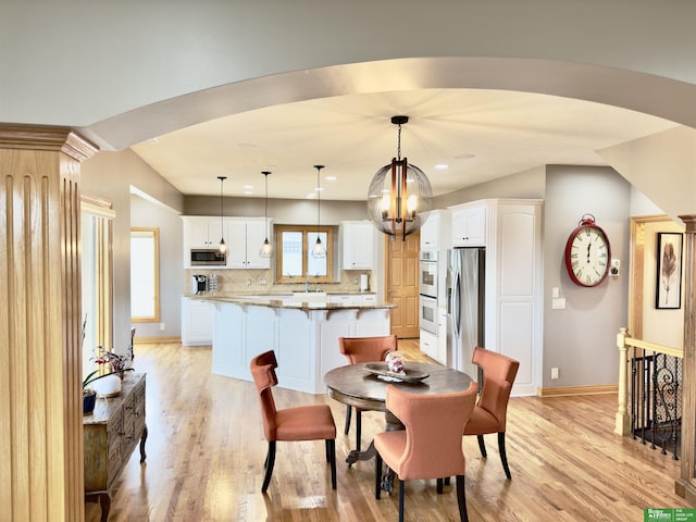 dining room with plenty of natural light, sink, light hardwood / wood-style floors, and a notable chandelier