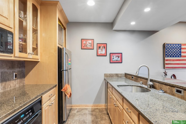 kitchen featuring sink, stainless steel fridge, black microwave, tasteful backsplash, and light stone countertops