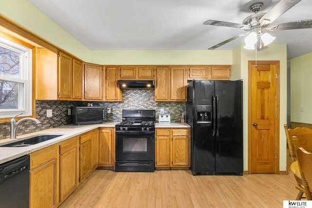 kitchen featuring sink, decorative backsplash, light hardwood / wood-style flooring, and black appliances