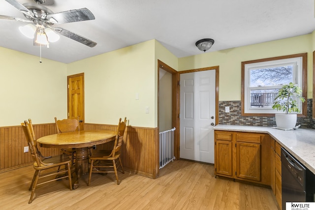 dining room featuring wood walls, ceiling fan, and light hardwood / wood-style flooring