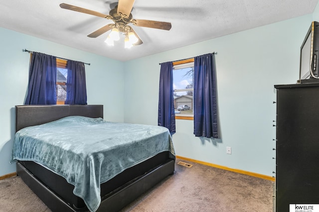 bedroom with ceiling fan, carpet flooring, and a textured ceiling