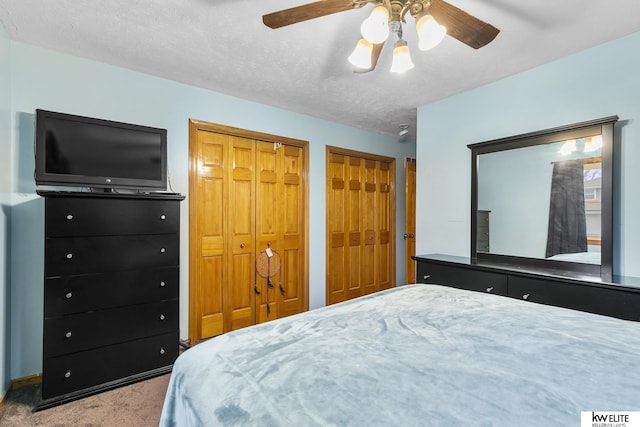 bedroom featuring multiple closets, ceiling fan, carpet, and a textured ceiling