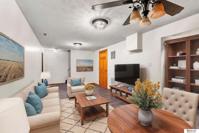 living room featuring ceiling fan, light hardwood / wood-style floors, and a textured ceiling