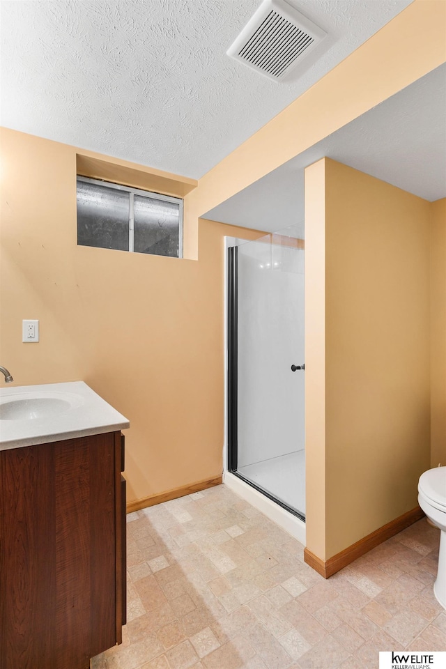 bathroom with vanity, toilet, an enclosed shower, and a textured ceiling