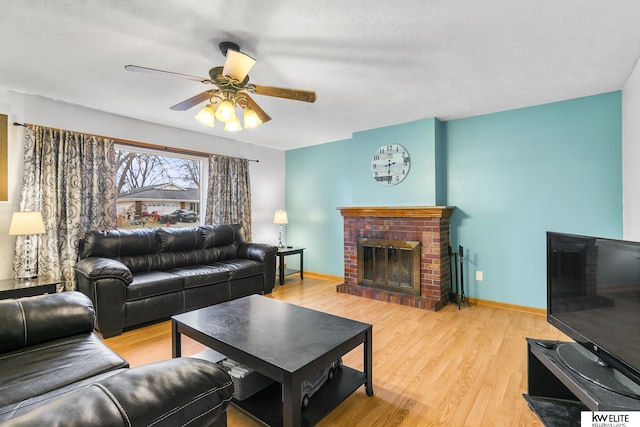 living room with ceiling fan, a fireplace, and light hardwood / wood-style floors