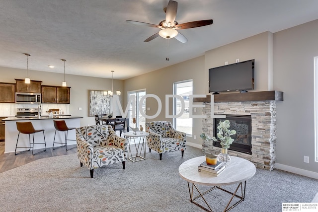 living room with ceiling fan, a textured ceiling, and a fireplace