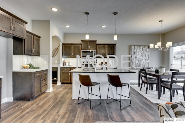 kitchen featuring dark brown cabinetry, hanging light fixtures, and a kitchen island with sink