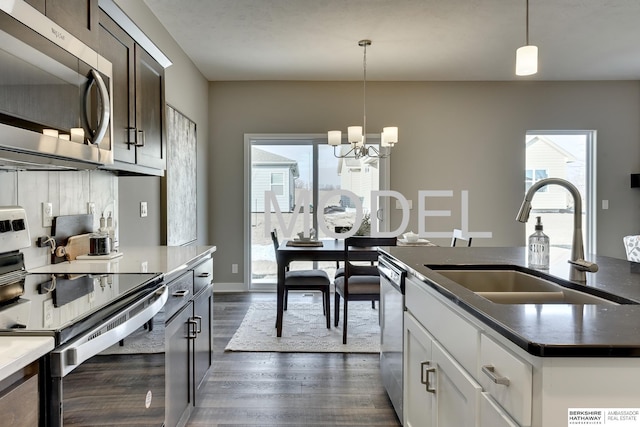 kitchen featuring sink, dark wood-type flooring, hanging light fixtures, stainless steel appliances, and white cabinets