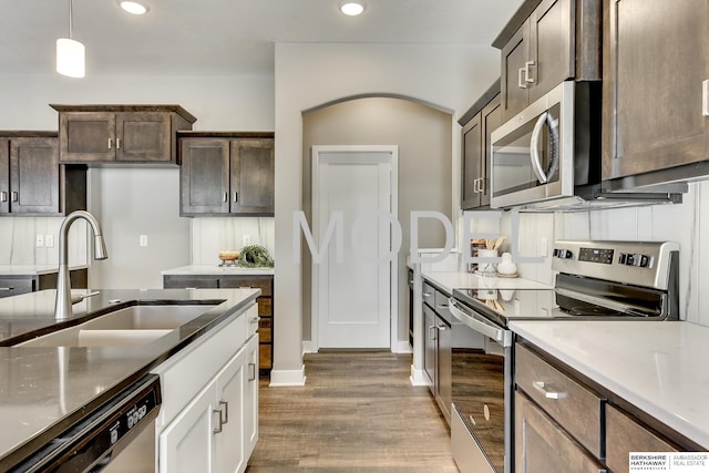 kitchen with appliances with stainless steel finishes, decorative light fixtures, white cabinetry, sink, and dark brown cabinetry