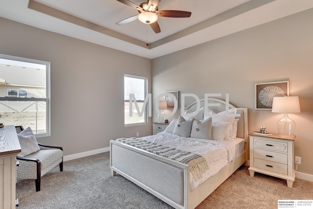 bedroom with multiple windows, light carpet, and a tray ceiling