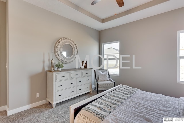 carpeted bedroom with multiple windows, a tray ceiling, and ceiling fan