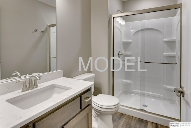 bathroom featuring toilet, hardwood / wood-style floors, vanity, and walk in shower