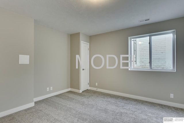 empty room with light colored carpet and a textured ceiling