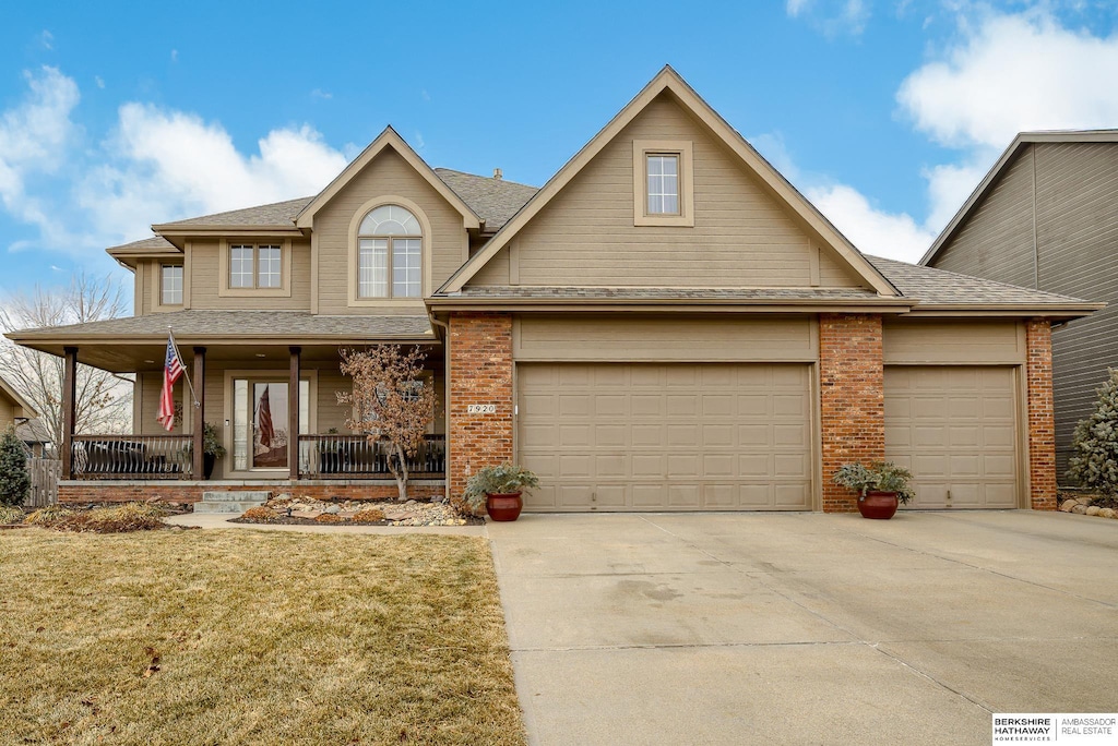 view of front of property featuring a garage, covered porch, and a front yard