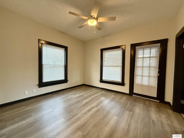 empty room featuring ceiling fan, a textured ceiling, and light hardwood / wood-style flooring