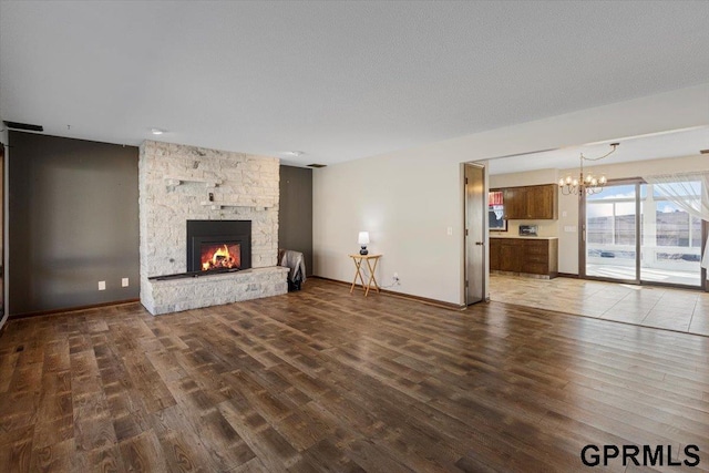 unfurnished living room with a chandelier, a fireplace, dark hardwood / wood-style flooring, and a textured ceiling