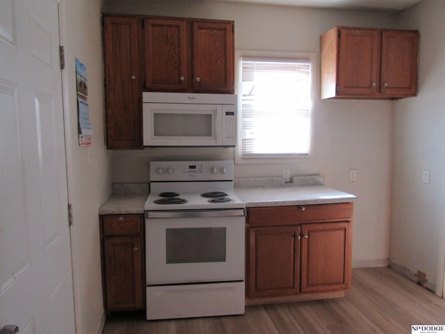 kitchen with white appliances, baseboards, brown cabinetry, light wood-style flooring, and light countertops