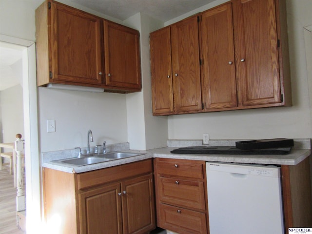 kitchen with dishwasher, light countertops, a sink, and brown cabinets