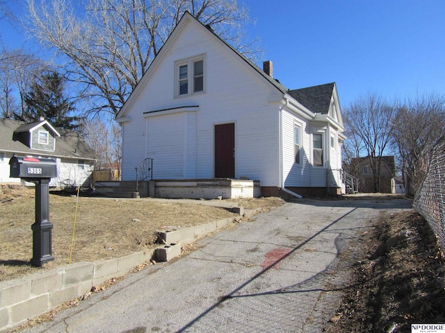 view of side of home featuring roof with shingles and a chimney