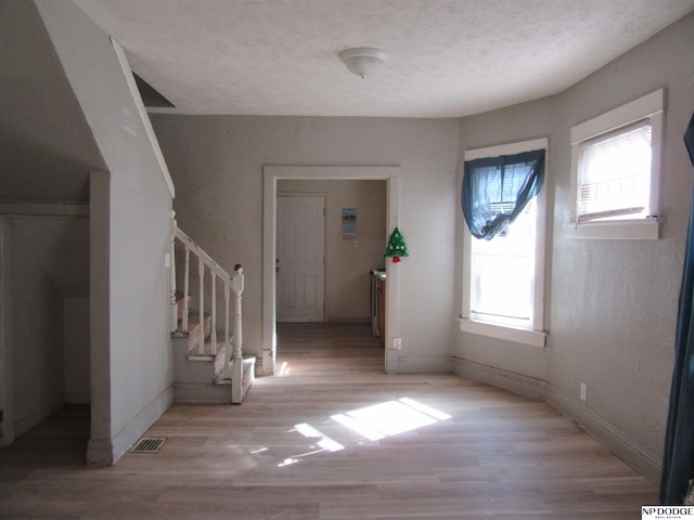 foyer with visible vents, light wood-style flooring, stairway, a textured ceiling, and baseboards