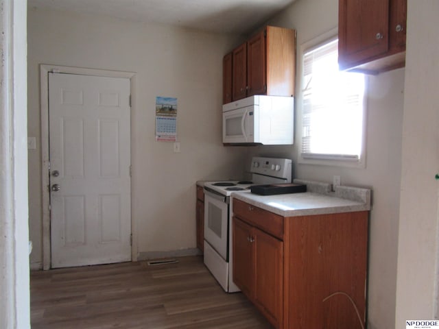 kitchen featuring brown cabinetry, light wood-type flooring, white appliances, and light countertops