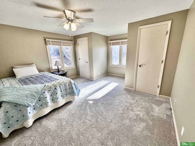 bedroom featuring multiple windows, ceiling fan, light colored carpet, and a textured ceiling