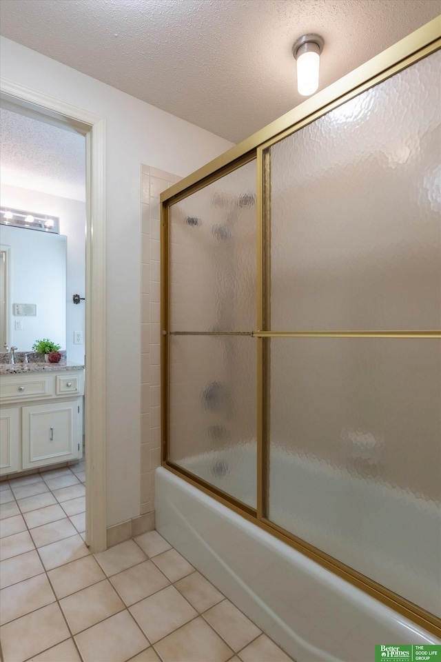 bathroom with bath / shower combo with glass door, tile patterned floors, a textured ceiling, and vanity