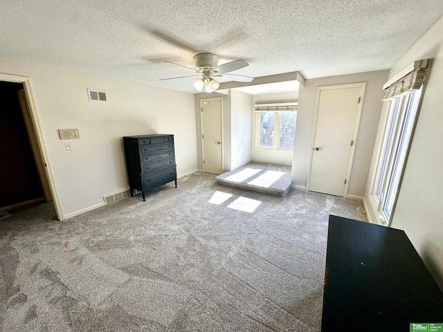 unfurnished bedroom featuring a textured ceiling, light colored carpet, and ceiling fan