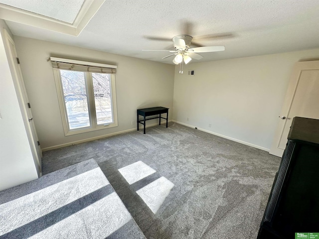 empty room with dark colored carpet, ceiling fan, and a textured ceiling