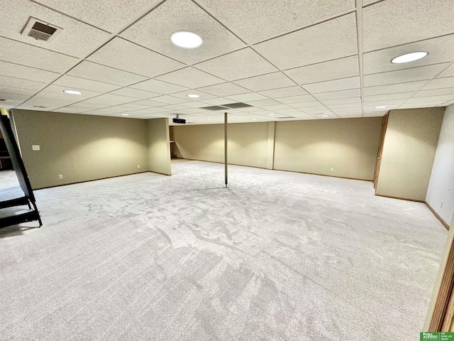 basement with a paneled ceiling and carpet