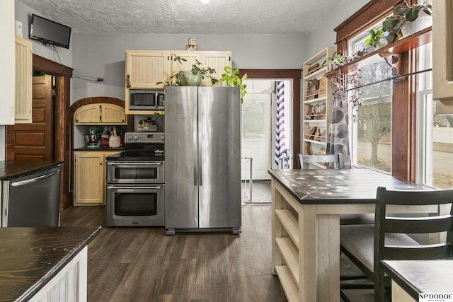 kitchen featuring appliances with stainless steel finishes, dark wood-type flooring, light brown cabinets, and a textured ceiling