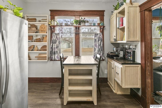 interior space featuring light brown cabinets, a healthy amount of sunlight, dark wood-type flooring, and stainless steel refrigerator