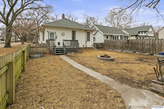 back of property with a deck and a fire pit