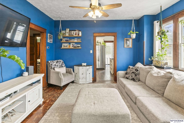 living room with ceiling fan, dark hardwood / wood-style flooring, and a textured ceiling