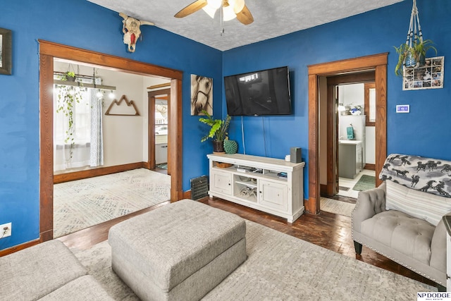 living room with ceiling fan, a textured ceiling, and dark hardwood / wood-style flooring