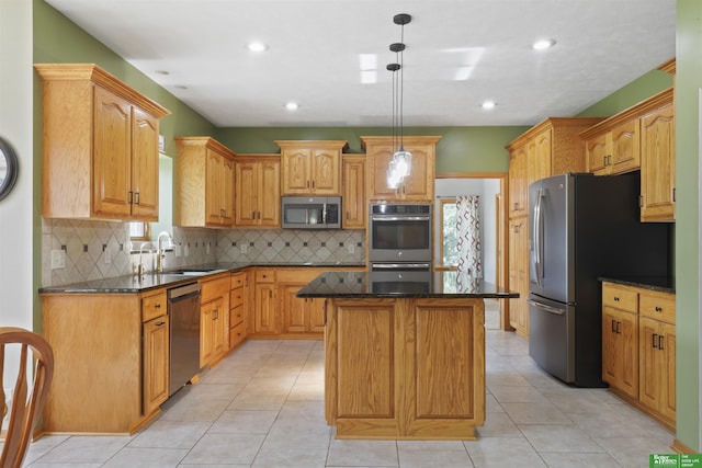 kitchen with pendant lighting, sink, dark stone countertops, stainless steel appliances, and a kitchen island